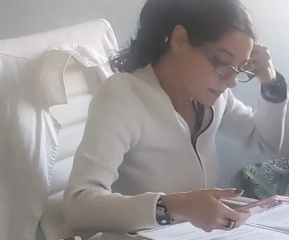 A woman sitting at the table looking down at her phone.